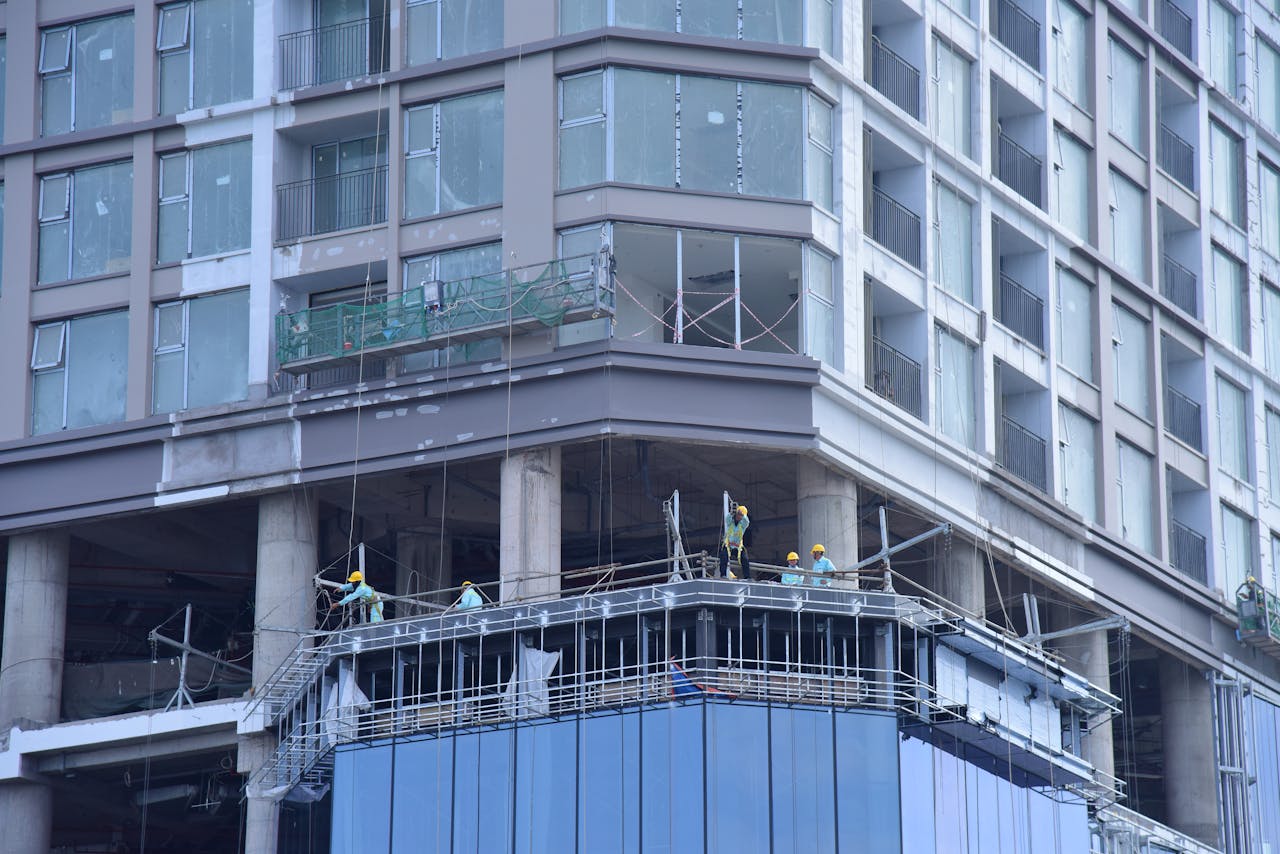 High-rise building construction with workers on site in urban setting.
