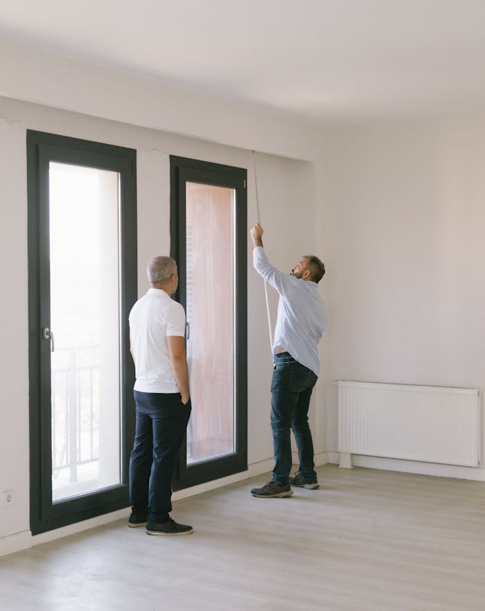 Two men measuring window dimensions in a bright Istanbul apartment.