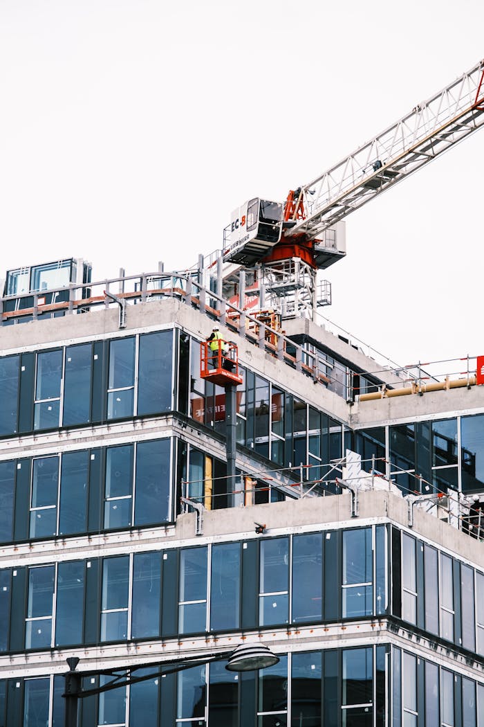 A construction site with a tower crane and modern glass building facade.